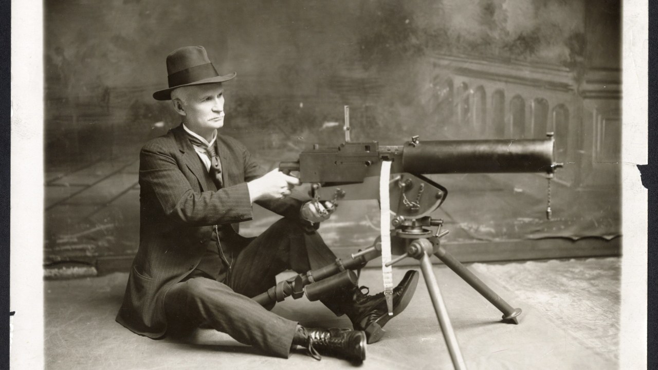 John Moses Browning, seated with one of his machine guns, in a photo from before his death in 1926.
