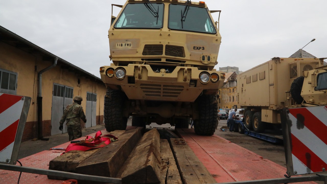 Tan M1087 FMTV expandable van truck on a flatbed