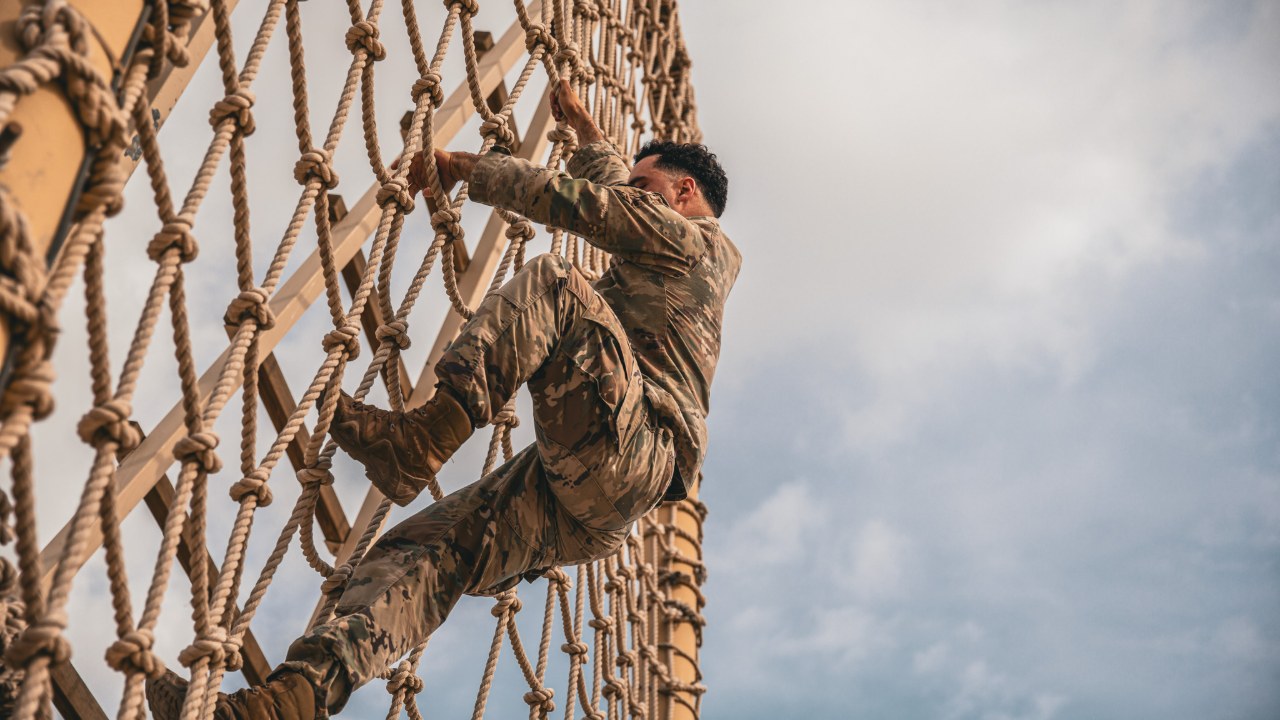 Soldier climbing a cargo net on an obstacle course