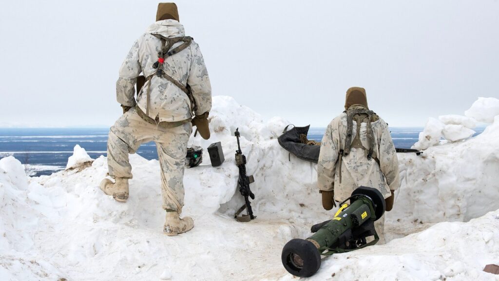Two 11th Airborne Division soldiers in white cold-weather gear in deep snow