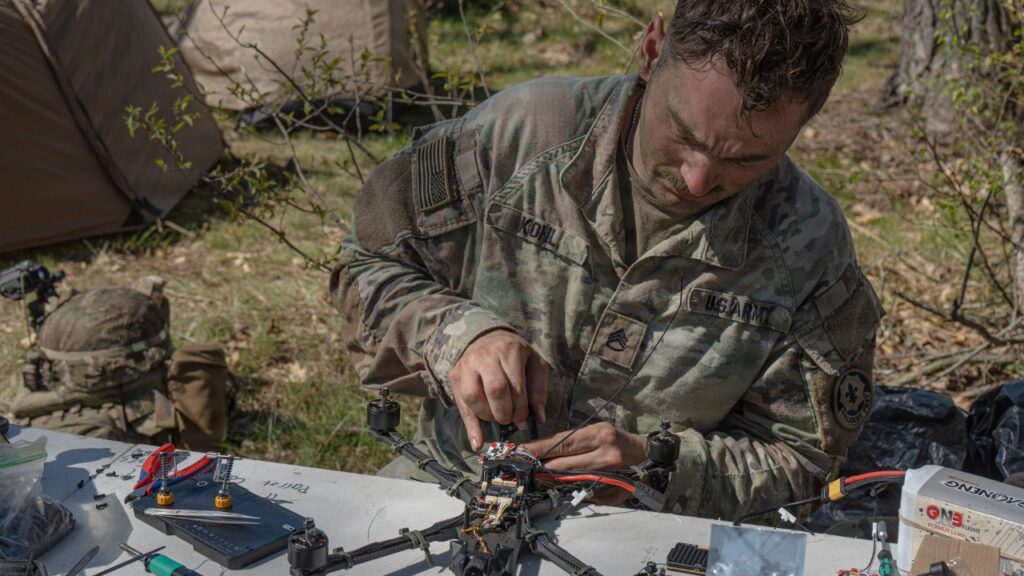 Soldier working on a small quadcopter drone at a field table