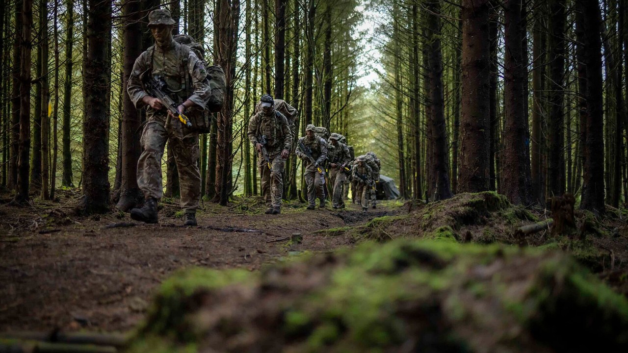 A patrol moves through woodland during Exercise Cambrian Patrol 2022 in Wales
