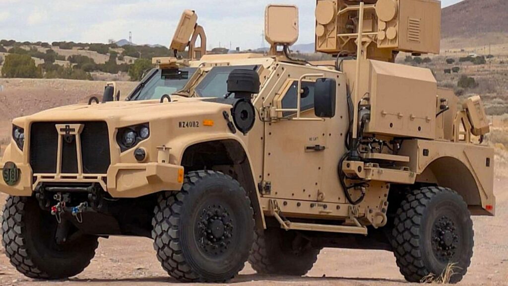 A tan JLTV carrying a laser turret in the desert