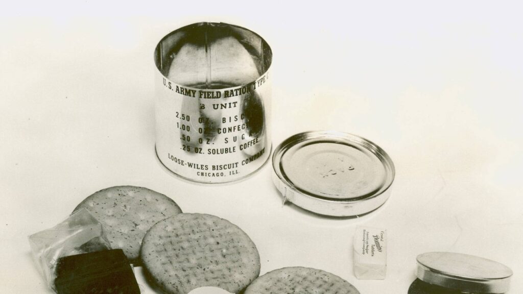 A 1941 C ration can with biscuits and small tins laid out beside it